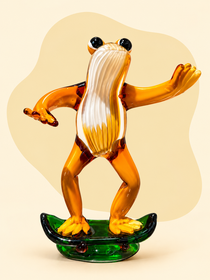 Glass frog on skateboard sculpture — front view