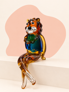 Seated rainbow glass lion sculpture with amber, blue, green, black and clear details.