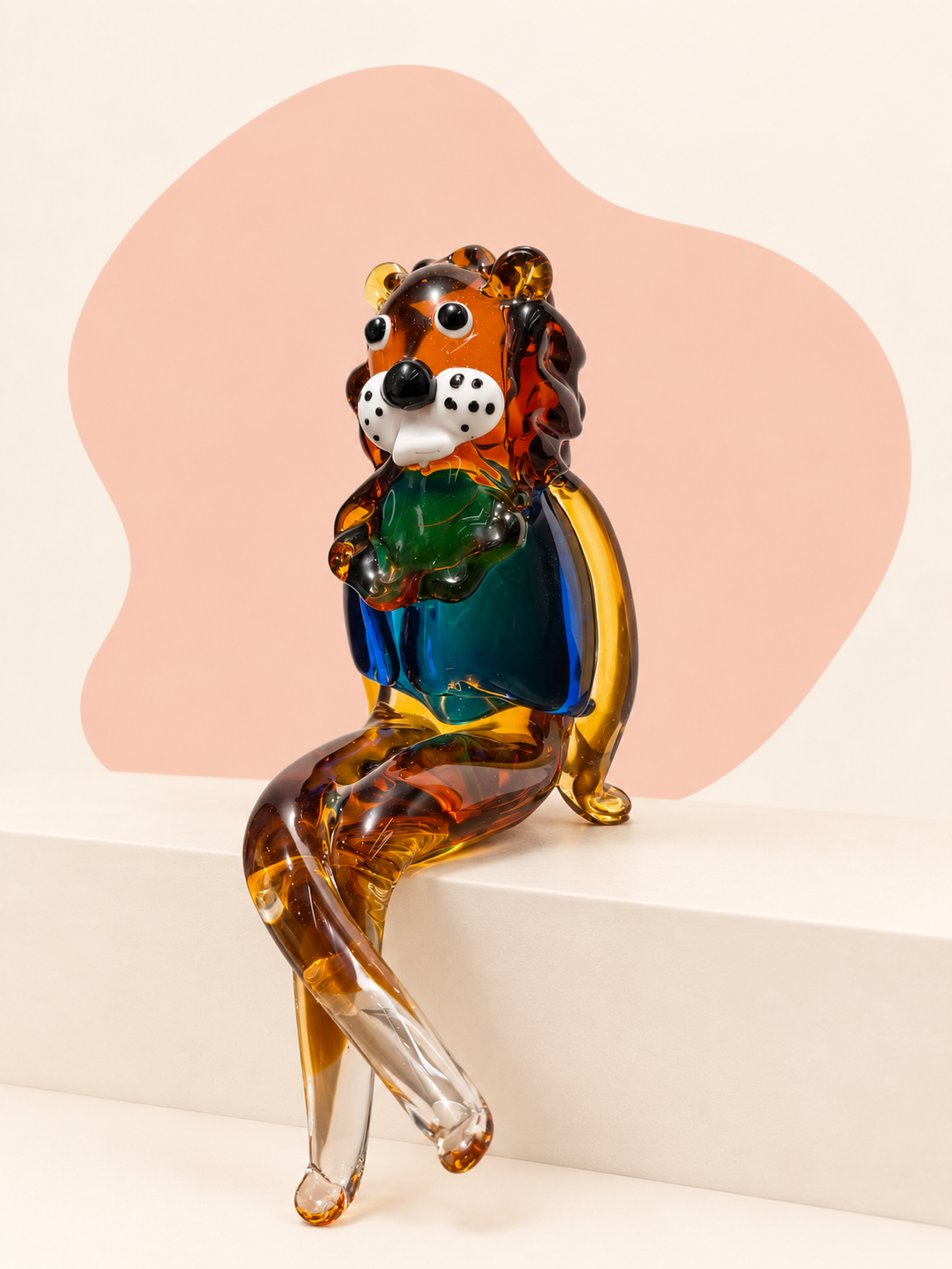 Seated rainbow glass lion sculpture with amber, blue, green, black and clear details.