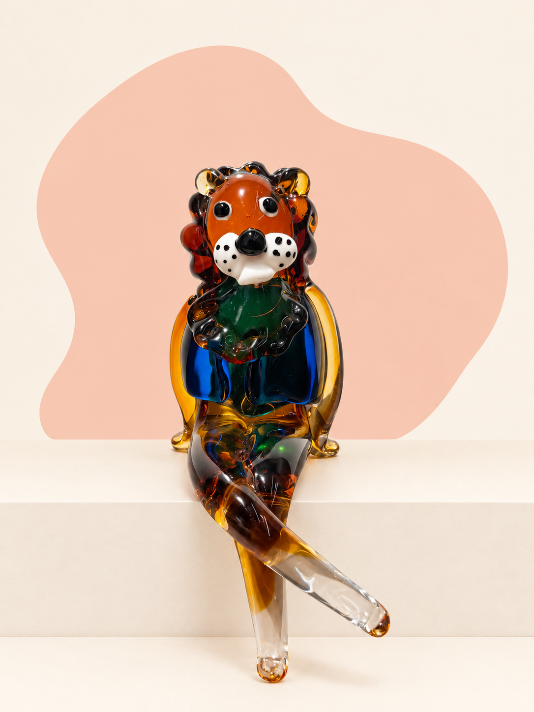 Seated rainbow glass lion sculpture with amber, blue, green, black and clear details.